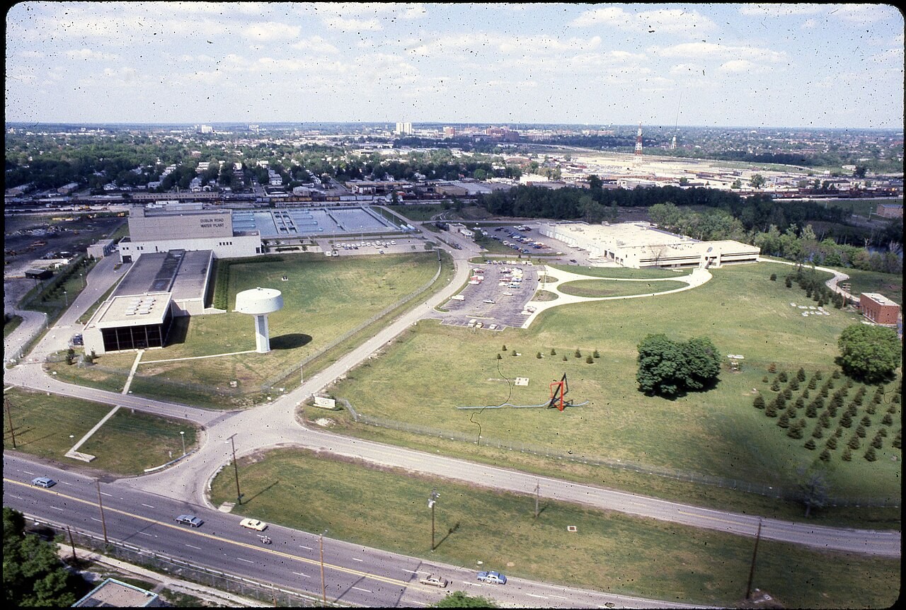 Aerial view of the Dublin Road Water Plant facility in Columbus, Ohio, showing plant buildings, water settling basins, an elevated white water tower, and Dublin Road in the foreground.