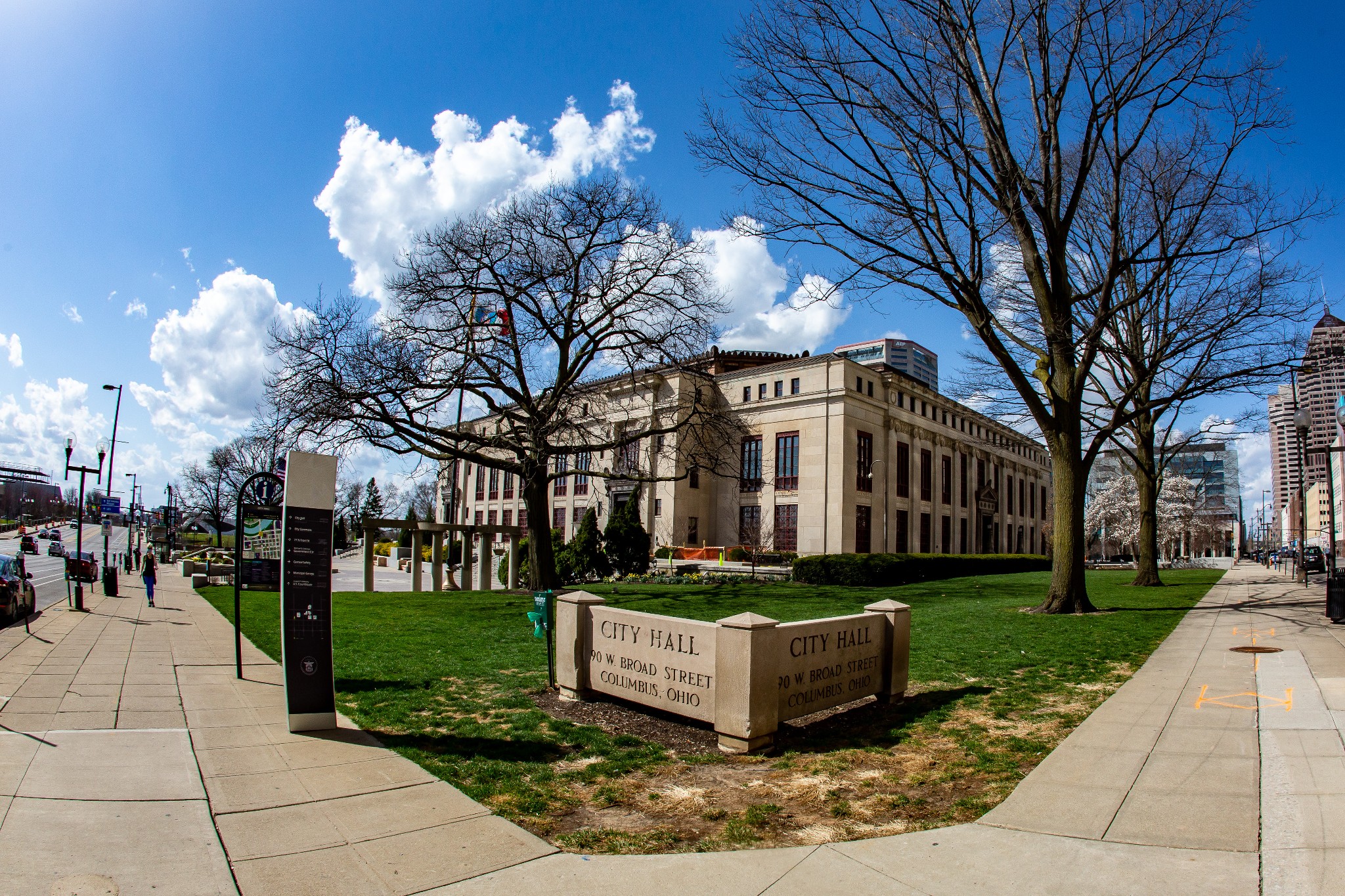 Wide-angle daytime view of Columbus City Hall showing the limestone facade, surrounding grounds, and an engraved stone sign reading City Hall 90 W. Broad Street.