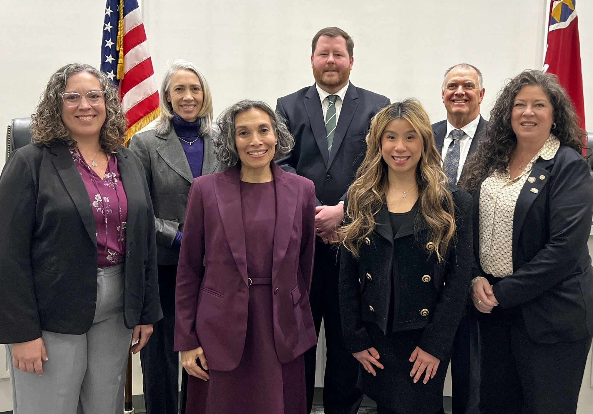 Worthington City Council members standing together in a formal portrait inside council chambers in front of U.S. and City of Worthington flags.
