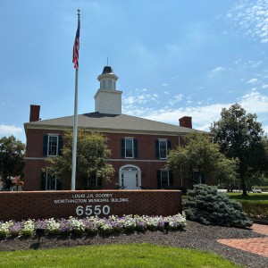 Exterior view of the Louis J.R. Goorey Worthington Municipal Building with a brick monument sign and American flag.