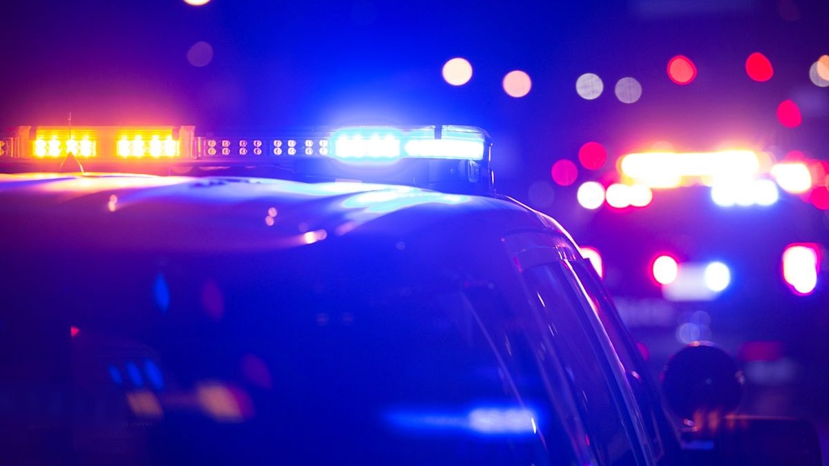 Close-up nighttime view of illuminated red and blue police emergency lights on a patrol vehicle.