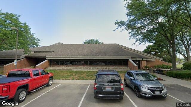 Exterior view of the low-profile brick and shingle-roofed Hilliard Municipal Building with cars parked in the front lot.