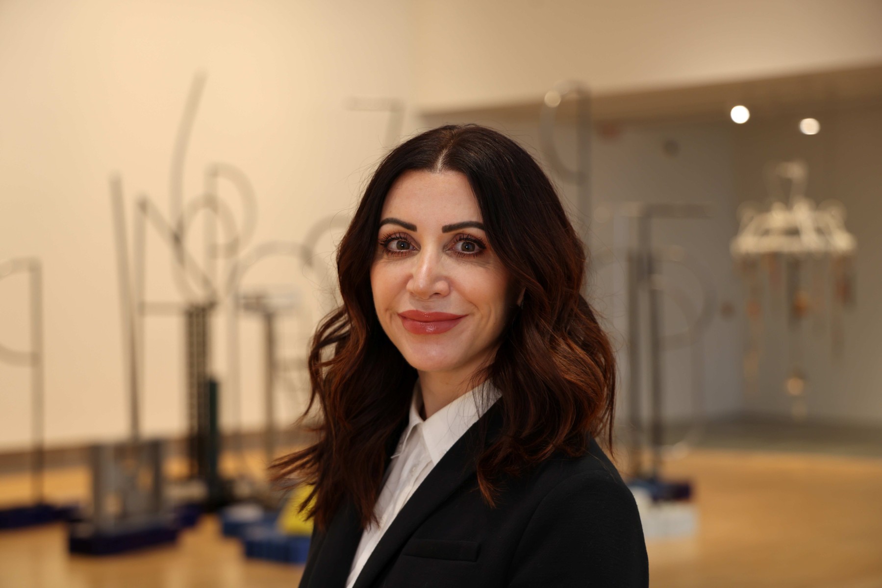 Cathy Predmore wearing a black blazer and white shirt, smiling in an art gallery