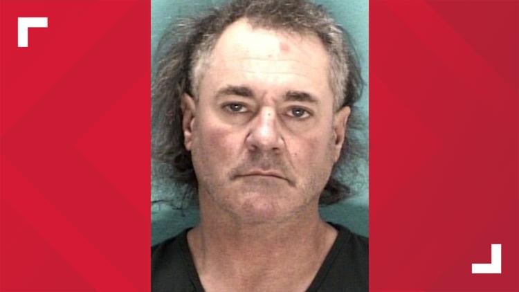 Booking mugshot of Derek Baldwin, showing a head-and-shoulders portrait of a middle-aged man with graying hair against a teal backdrop.