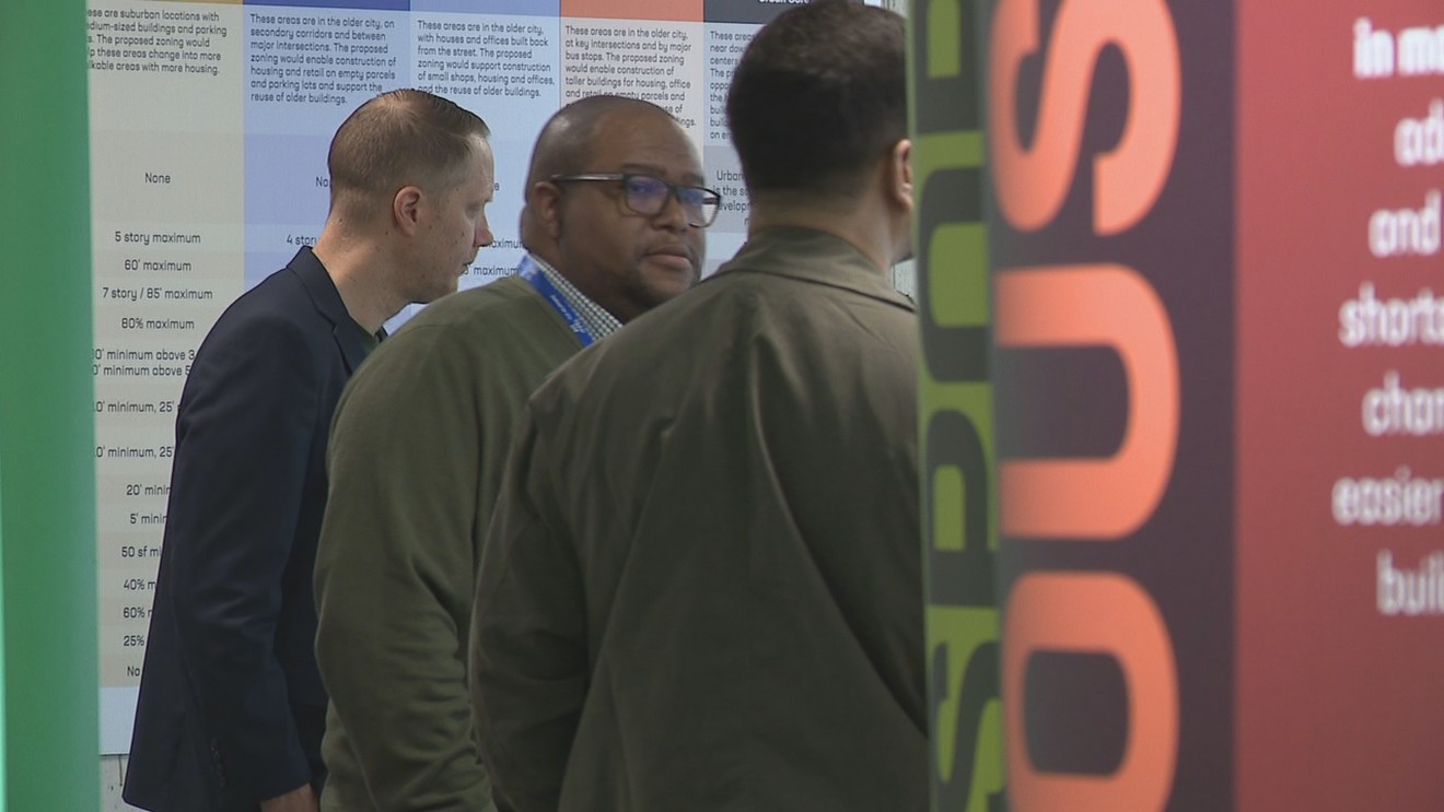 Attendees at the Columbus Zone In Gallery examining a detailed wall chart detailing proposed building height and density regulations.