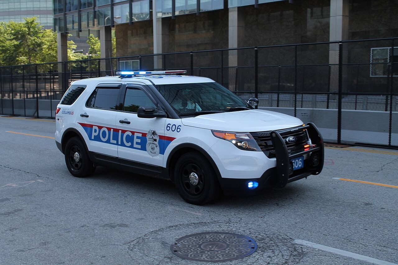 Columbus Division of Police patrol vehicle with emergency lights illuminated on a city street.