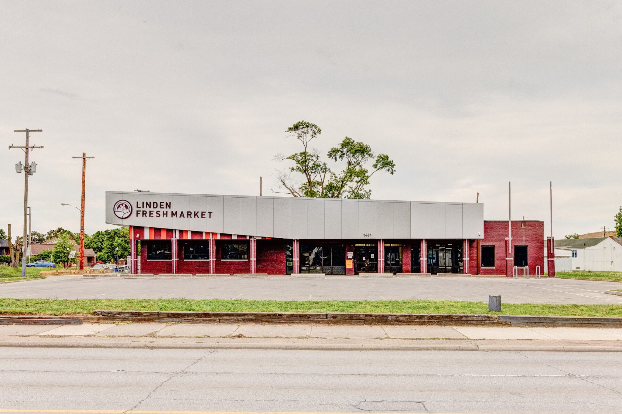 Straight-on wide photograph of the Linden Fresh Market building at 1464 Cleveland Avenue with maroon brick facade, modern grey fascia, and empty parking lot.