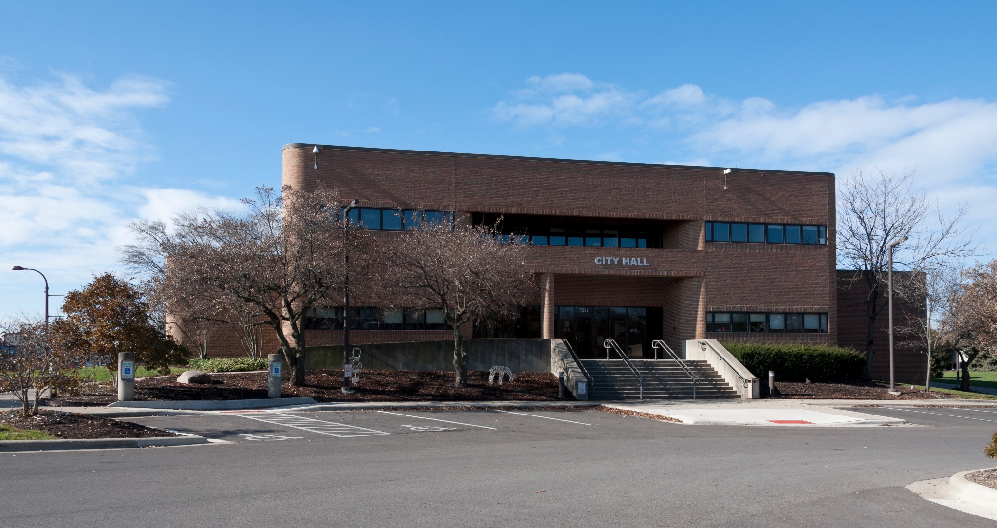 Exterior view of the Reynoldsburg City Hall brick building showing the main entrance stairs and City Hall signage.