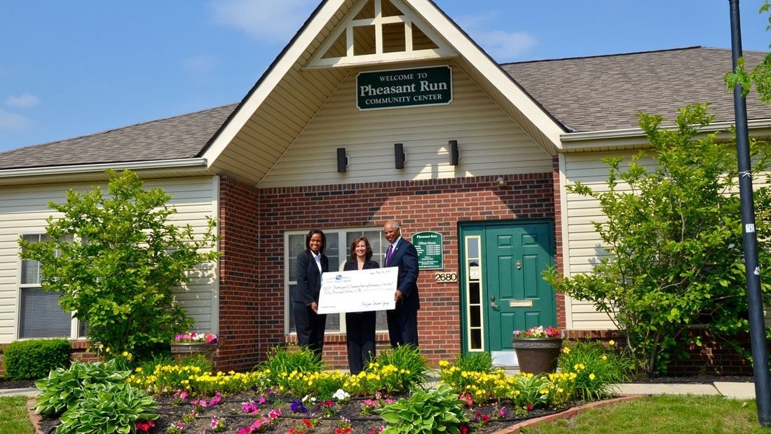Exterior view of the Pheasant Run Community Center building with tan siding, red brick accents, and entrance signage.